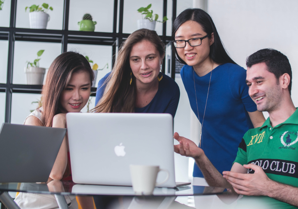 大人数で1台のパソコンの前で話し合っている写真